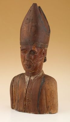 une vieille statue en bois représentant un homme coiffé d'un chapeau