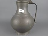 an old silver pitcher with a handle on a gray background