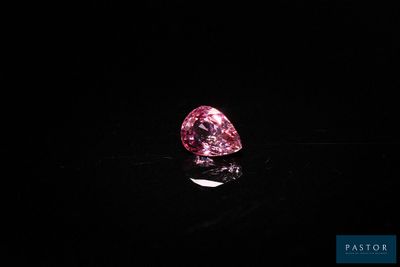un diamant rose sur une surface noire dans l'obscurité