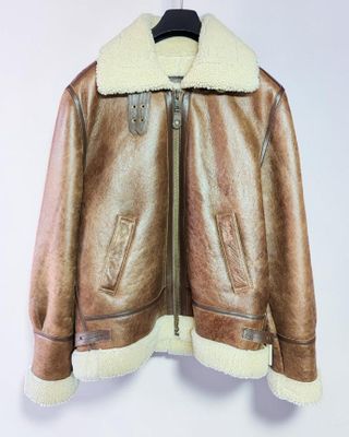 une veste en cuir marron suspendue à un cintre sur un mur blanc