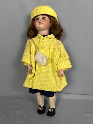 poupée vêtue d'un imperméable jaune et de chaussures noires, avec un sac blanc