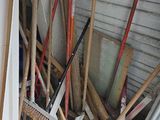 a pile of brooms and rakes outside of a building