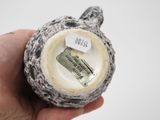 a person holding a small ceramic object with a tag on it