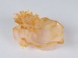 a yellow flower in a shell on a white surface