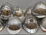 six casques de pompier argentés posés sur une table blanche