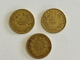 three gold coins sitting on top of a white surface next to each other