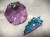 une assiette violette ornée d'une fleur verte et une assiette violette ornée d'une fleur verte