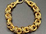 a close up of a gold chain bracelet on a table
