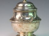 a silver vase with a lid sitting on a table