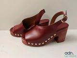 Les chaussures de cette femme sont en cuir rouge et ornées de clous dorés.