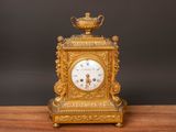 a gold clock sitting on a wooden table with a black background