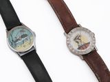 two watches that are next to each other on a white surface