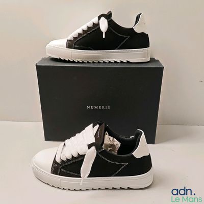 une paire de baskets noires et blanches dans une boîte noire