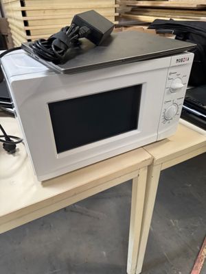 a microwave sitting on a table with a charger on top of it