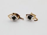 a pair of gold and silver cufflinks with a green stone