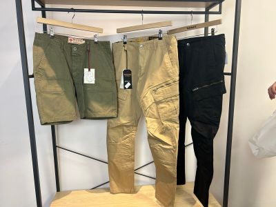 trois paires de pantalons suspendues à un portant dans un magasin de vêtements