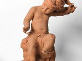 statue d'un garçon assis sur un rocher, tenant un oiseau dans la main