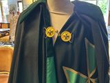 a black cape with a green and gold cross on it