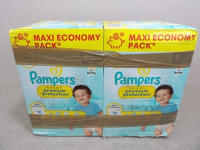 Deux boîtes de couches Pampers pour bébés sont entourées d'un ruban marron