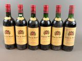 six bottles of wine are lined up in a row on a table
