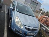 une voiture bleue garée sur un parking près d'une clôture
