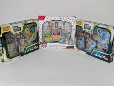 trois cartes à collectionner Pokémon différentes dans une boîte posée sur une surface blanche