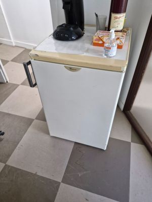 a small white refrigerator in the corner of a room