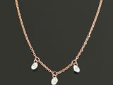 a gold chain necklace with three charms on a black background