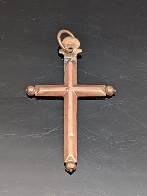 une croix en bois posée sur une surface noire, dans laquelle est insérée une clé