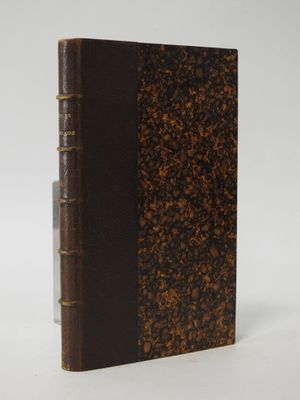 an old book with a brown cover sitting on top of a white surface