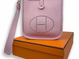 un sac à main rose posé sur une boîte, à côté d'une boîte orange