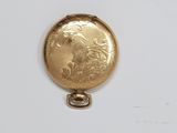 a gold colored pocket watch with a picture of a woman on it