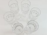 six glasses of water sitting in a circle on a white surface