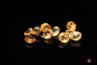 a close up of a pair of yellow sapphires on a black surface