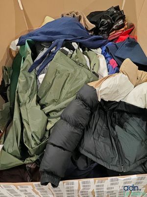 une boîte en carton remplie de vêtements, ainsi que des vêtements éparpillés sur le sol