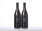 two bottles of wine sitting on top of a table next to each other
