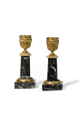 paire de bougeoirs noirs et dorés sur des socles en marbre