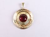a close up of a gold pendant with a red stone