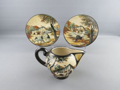 a pitcher and two plates with a painting on it
