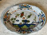a plate with a peacock on it sitting on a table