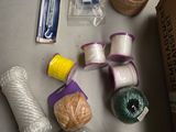 une table sur laquelle se trouvent plusieurs objets, notamment un rouleau de ficelle, une bobine de ficelle et une bobine de ficelle double