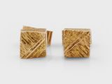 une paire de boucles d'oreilles carrées en or à la surface texturée