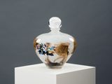 un vase en verre orné d'une image, posé sur un socle blanc