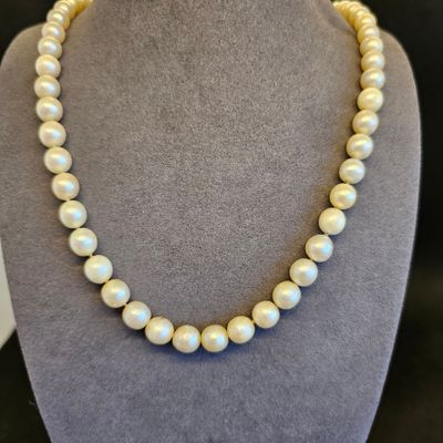 un collier de perles blanches sur un mannequin avec un fermoir en or