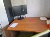 a desk with a computer and a refrigerator in the corner
