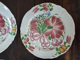 two plates with flowers painted on them sitting on a table