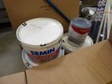 a bucket of paint and a can of paint sitting on a table
