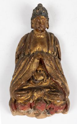 statue d'un Bouddha assis tenant un crâne, posée sur une surface blanche