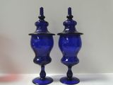 two blue glass vases sitting on a white table