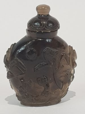 a brown vase with a lid sitting on a white surface